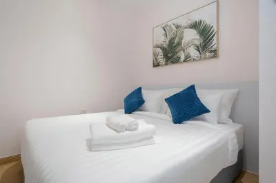 a white bed with two towels and blue pillows at Espuma Patong pool villa in Patong Beach