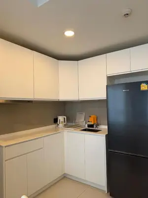 a kitchen with white cabinets and a black refrigerator at Sky Park Family Comfort in Laguna Phuket