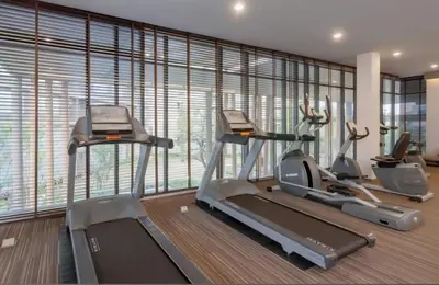 a gym with three tread machines in a room with windows at studio room dami in Kathu