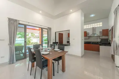 a kitchen and dining room with a wooden table and chairs at Orchid Pool Villa 8 Rawai in Rawai Beach