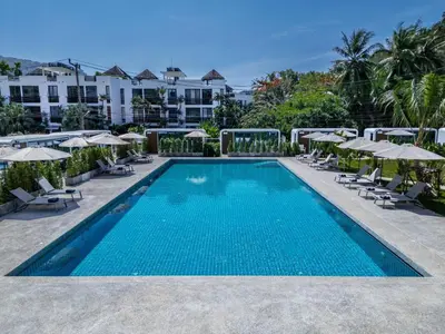a swimming pool with chairs and umbrellas at a resort at Apple House Phuket a cozy home terrace &pool&beach in Ban Lum Fuang