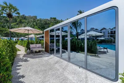 a building with glass windows and a pool at Apple House Bangtao with terrace Pool & Beach in Ban Lum Fuang