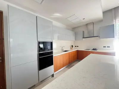 a kitchen with white cabinets and a black appliance at Anchan Grand Residence Bangtao in Ban Pak Lak