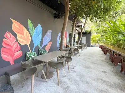 a row of tables and chairs with a mural on a wall at Seaside Apple House, Pool & Morning Breakfast in Ban Lum Fuang