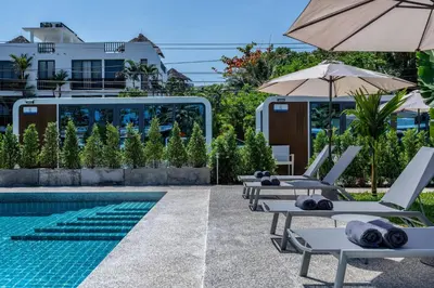a pool with chaise lounge chairs and an umbrella at Apple House Bangtao 1 Min Beach Pool & Breakfast in Ban Lum Fuang