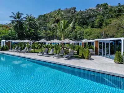 a pool at a resort with lounge chairs and umbrellas at Apple House Phuket Near Beach with Pool & Terrace in Ban Lum Fuang