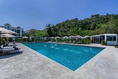 a swimming pool with chairs and umbrellas at a resort at Private Pool Apple House, Sea & Breakfast Bangtao in Ban Lum Fuang