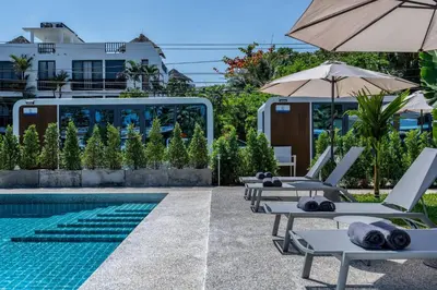 a pool with lounge chairs and an umbrella at Private Pool Apple House, Sea & Breakfast Bangtao in Ban Lum Fuang