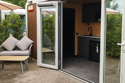 a sliding glass door leading into a kitchen with a couch at Apple House with Pool breakfast Surin Beach in Ban Lum Fuang