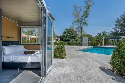 a bed in a glass room next to a swimming pool at Bangtao Apple House Peace by the Sea in Ban Lum Fuang