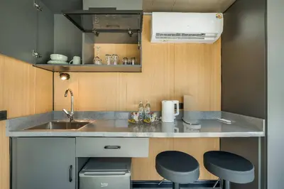 a small kitchen with a sink and two stools at Bangtao Apple House Peace by the Sea in Ban Lum Fuang
