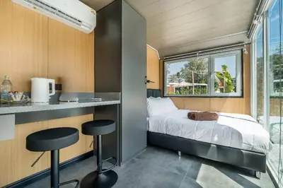 a small bedroom with a bed and two stools at Apple House Bangtao with Pool & Terrace, beach in Ban Lum Fuang