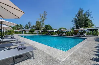 a swimming pool with chairs and umbrellas at a resort at Apple House Stylish Seaside Retreat with Breakfast in Ban Lum Fuang