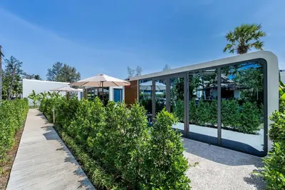a modern house with glass walls and trees at Cozy Apple House Bangtao Poolside Beach Retreat in Ban Lum Fuang