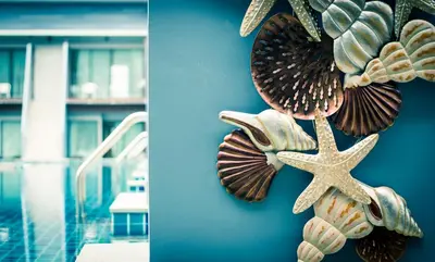 two pictures of a wall with seashells and a building at The Phu Beach Hotel - SHA Plus in Ao Nang Beach