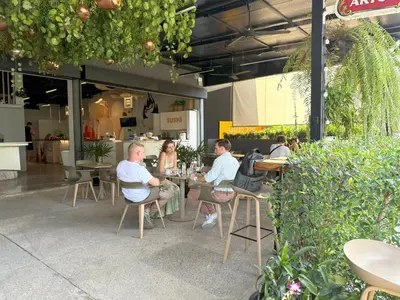 a group of people sitting at tables in a restaurant at Apple House Bangtao Pool, Terrace & Breakfast in Ban Lum Fuang