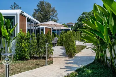 a walkway with an umbrella next to a building at Apple House Seaside Escape with Pool & Breakfast in Ban Lum Fuang