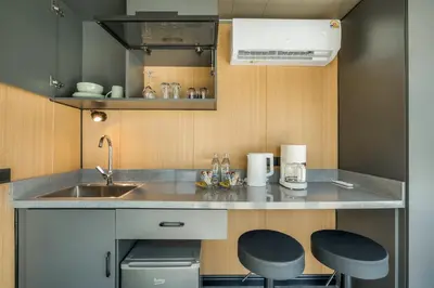 a small kitchen with a sink and two stools at Apple House Phuket Pool, Terrace, Breakfast, Beach in Ban Lum Fuang
