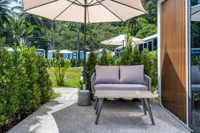 a chair and an umbrella on a patio at Apple House by the Sea, Bangtao Area in Ban Lum Fuang