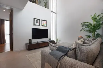 a living room with a couch and a flat screen tv at Peaceful Penthouse @ Lotus Gardens Layan Beach in Layan Beach