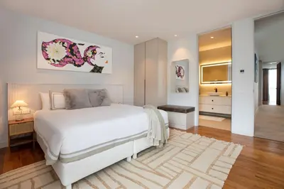 a white bedroom with a large bed and a bathroom at Peaceful Penthouse @ Lotus Gardens Layan Beach in Layan Beach