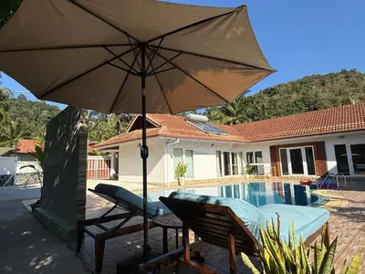 a patio with an umbrella next to a swimming pool at B&K private pool Villa in Rawai Beach