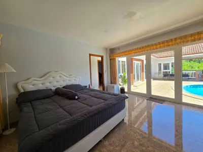 a bedroom with a large bed and a swimming pool at B&K private pool Villa in Rawai Beach
