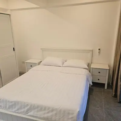 a bedroom with a white bed and two night stands at Kamala House in Kamala Beach