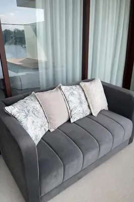 a couch with three pillows on it in a room at Потрясающие апартаменты на Банг Тао in Laguna Phuket