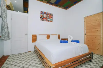 a bedroom with a white bed with a wooden headboard at Beautiful 4 bedroom ocean view white house, steps from the beach Rawai Beach in Nai Harn Beach