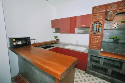 a kitchen with red cabinets and a wooden counter top at Beautiful 4 bedroom ocean view white house, steps from the beach Rawai Beach in Nai Harn Beach