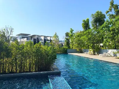 a swimming pool with blue water in front of a building at Laguna Cozy 3 bedroom town house 800m to beach in Laguna Phuket