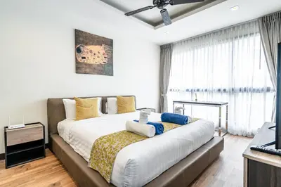 a bedroom with a large bed and a television at Laguna Cozy 3 bedroom town house 800m to beach in Laguna Phuket