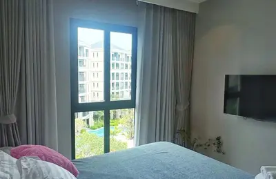 a bedroom with a window with a view of a building at Bright Modern Phuket Home Title Legendary Bangtao in Bang Tao Beach