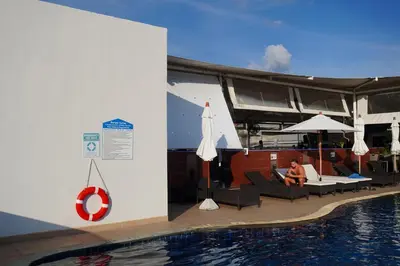 a woman sitting on a chair next to a swimming pool at Patong Condo Tub, Roof Pool & 2-min to Beach in Patong Beach