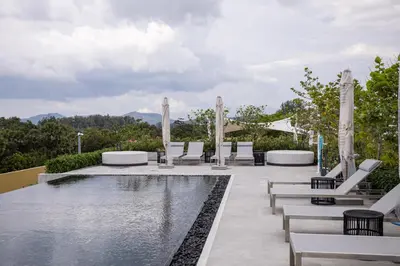 a pool with white lounge chairs next to a pool at Premium 1BR Laguna, 200m to the Beach in Bang Tao in Bang Tao Beach