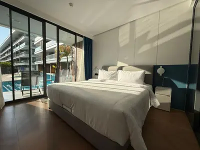 a bedroom with a large bed and a pool at Sunshine BEACH FRONT access to the pool in Layan Beach