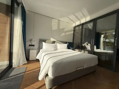 a bedroom with a large white bed and a window at Sunshine BEACH FRONT access to the pool in Layan Beach