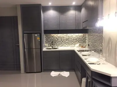 a kitchen with black cabinets and a stainless steel refrigerator at luxury apartment at Kamala in Kamala Beach