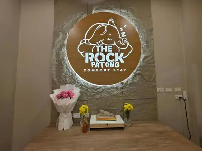 a room with a sign with flowers and a table at The Rock Poshtel Patong in Patong Beach
