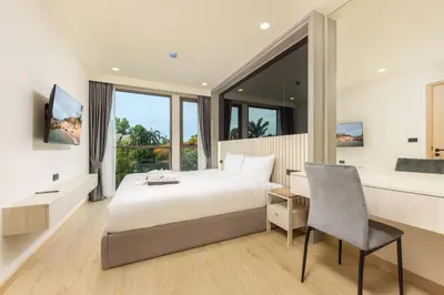 a bedroom with a bed and a desk and a chair at Suite Salina 2BR Pool Gym Access Ozone in Laguna Phuket
