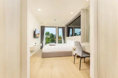 a bedroom with a bed and a desk and a chair at Suite Salina 2BR Pool Gym Access Ozone in Laguna Phuket