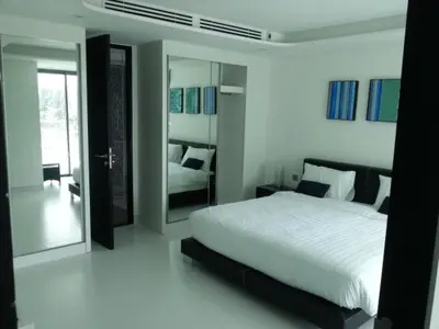 a white bedroom with a bed and a mirror at Resort Sea View Apartment Patong in Patong Beach