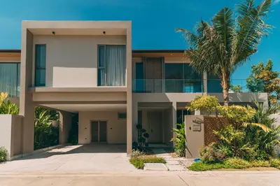 a building with palm trees in front of it at Grand View Family Villa 5 min to Beach in Ban Thalat Choeng Thale