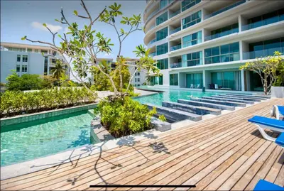 a swimming pool with a wooden deck and a building at Karon Beach Forest View in Ban Karon