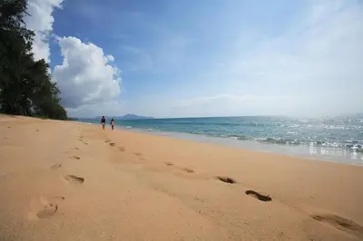 two people walking on a beach with footprints in the sand at CC620 View of Green Hills in Ban Mai Salae