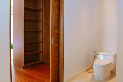 a bathroom with a toilet and a wooden closet at Anchan Flora Luxury 2BR Pool Villa in Thalang