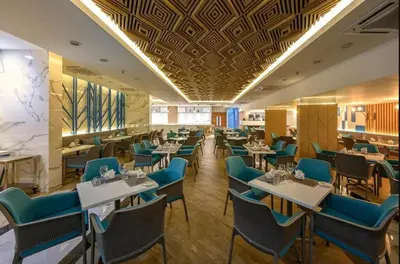 a dining room with tables and blue chairs at C109 Beachfront Seaside Escape Pool Access in Ban Saiyuan (1)