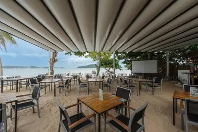 a restaurant with tables and chairs on the beach at C109 Beachfront Seaside Escape Pool Access in Ban Saiyuan (1)