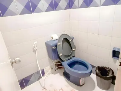 a blue toilet in a bathroom with purple and white tiles at XX Mitr Inn Phuket Mueang Kao - มิตร อินน์ ภูเก็ต โอลทาวน์ in Phuket Town